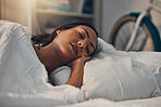 A beautiful young mixed race woman sleeping in a soft comfortable bed at home. One hispanic female feeling exhausted and resting in a comforting bed