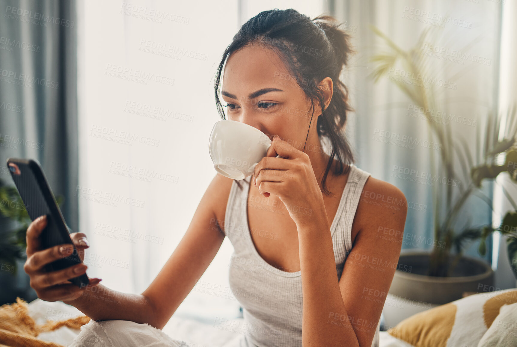 Buy stock photo A beautiful young Hispanic woman enjoying a warm cup of coffee for breakfast. One mixed race female drinking tea while checking her social media