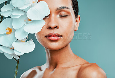 Buy stock photo Studio portrait of an attractive young mixed race woman posing with a orchid against a green background. Latin female posing with a plant with her smooth soft skin