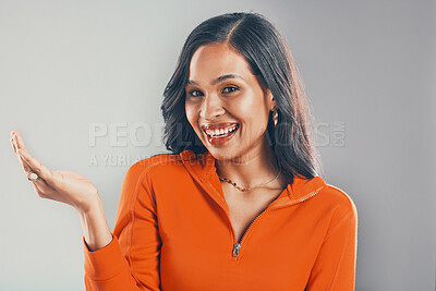 Buy stock photo Portrait of smiling mixed race woman isolated on grey studio background with copyspace and showing promotion. Beautiful happy young hispanic standing alone and marketing deal. Model feeling confident