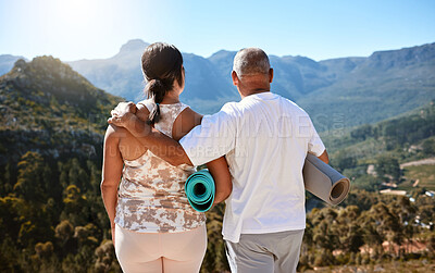 Buy stock photo Rear view of a active mature couple holding yoga mats while admiring a mountain view. Senior couple living a healthy lifestyle and doing fitness training outdoors