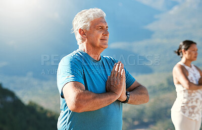 Senior man meditating with joined hands and closed eyes breathing deeply. Mature people doing yoga in nature living a healthy active lifestyle in retirement