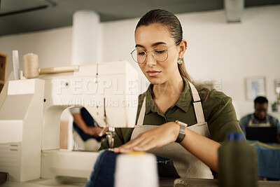 Buy stock photo Mixed race designer sewing on a machine. Young fashion designer stitching denim fabric. Serious tailor working in her studio. Creative entrepreneur sewing material on sewing machine
