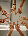 Closeup of hands of coworkers making peace signs in a star shape. Colleagues forming peace signs from below. Group of businesspeople collaborating together. Businesspeople joined together in unity
