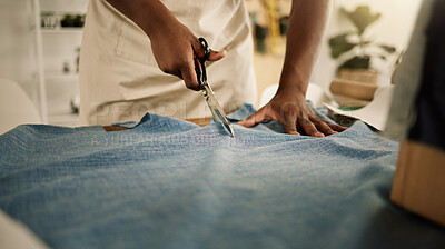 Buy stock photo Creative designer cutting his fabric. Closeup of a tailor cutting denim material using a scissor. Fashion designer working in his studio. Entrepreneur cutting his textile on a table