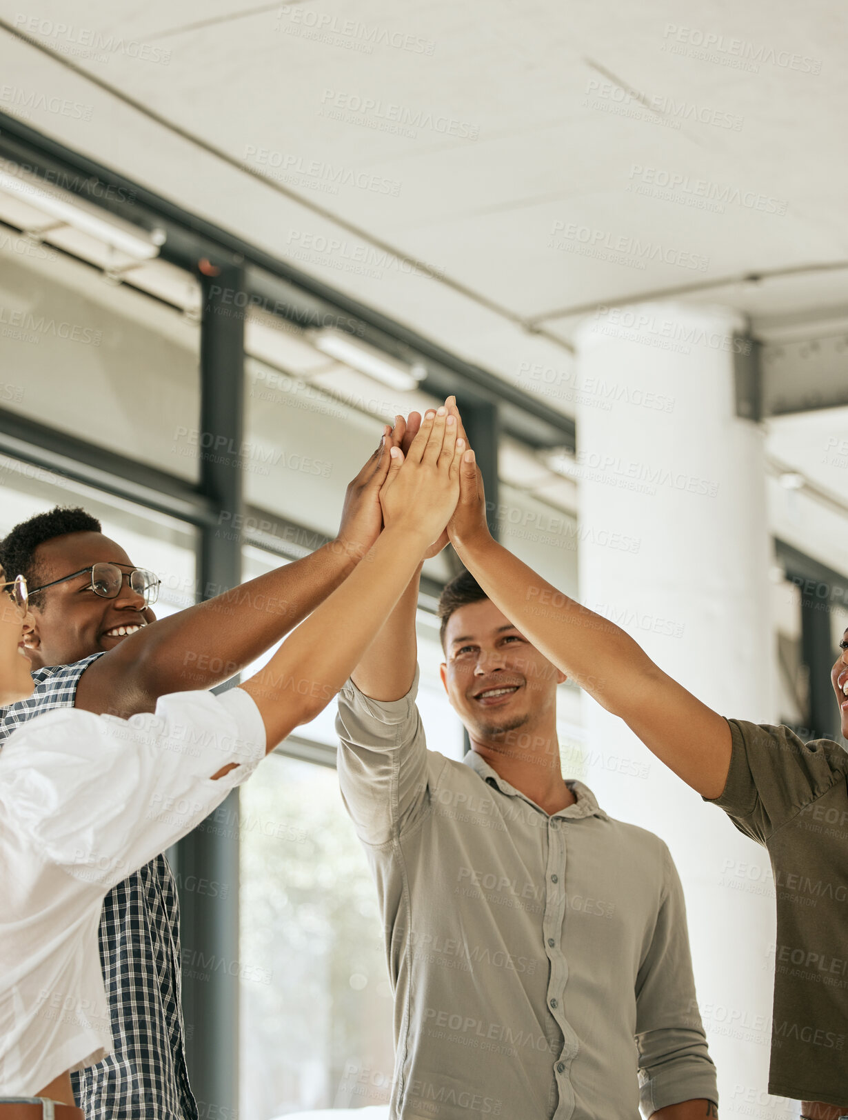 Buy stock photo Smiling creative business team standing in office and giving high five during team building. Diverse business people celebrating their success together at startup