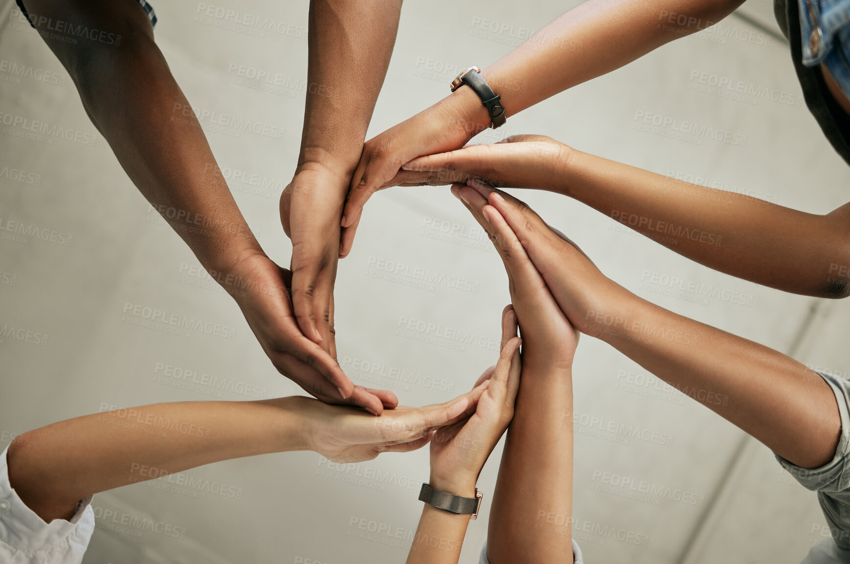 Buy stock photo Close up of a group of colleagues putting hands together to form a circle in the office from below. Creative team joining hands and showing unity in teamwork