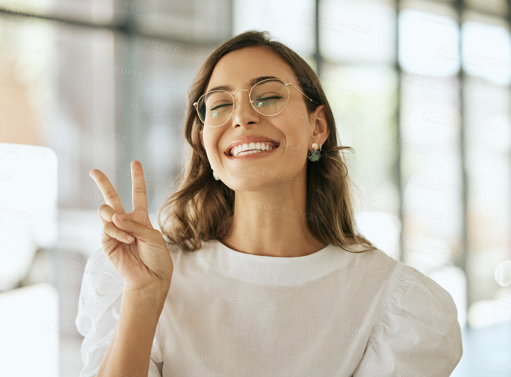 Buy stock photo Young excited professional with glasses gesturing peace sigh. Playful business woman entrepreneur showing victory sign in an office