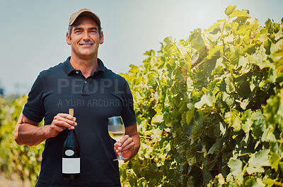 Buy stock photo Portrait of one smiling farmer holding a bottle and glass of white wine on his farm. Happy caucasian man with wineglass filled with alcohol for tasting during summer on vineyard. Weekend wine tasting