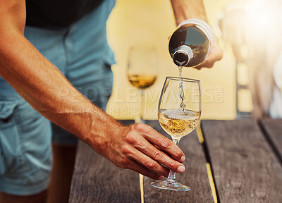 Buy stock photo Closeup of unknown farmer pouring white wine into wineglass on farm. Caucasian man holding a bottle and filling a glass with alcohol for tasting during summer on his vineyard. Weekend wine tasting