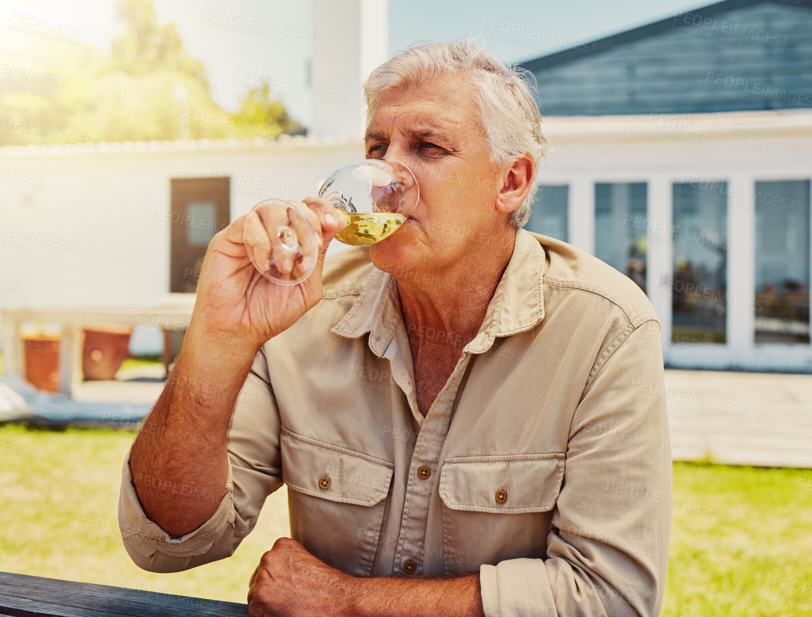 Buy stock photo One senior caucasian man sitting alone and drinking glass of white wine during wine tasting on a vineyard. Elderly caucasian man holding and enjoying alcohol from a wineglass on farm during a weekend