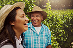 Smiling mixed race couple bonding on vineyard. Happy hispanic husband and wife laughing and enjoying day on a farm after wine tasting during a weekend. Man and woman wearing hats and standing together