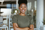Young happy african american businesswoman standing with her arms crossed alone at work. One cheerful black woman with an afro smiling while standing in an office
