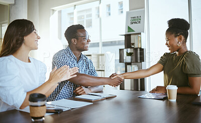 Young happy businesspeople shaking hands in a meeting with a colleague clapping at work. Cheerful hispanic businesswoman clapping hands for african american coworkers shaking hands