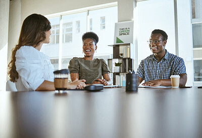 Buy stock photo Three young happy businesspeople having a meeting while sitting at a table at work. Cheerful business professionals talking and planning in an office together