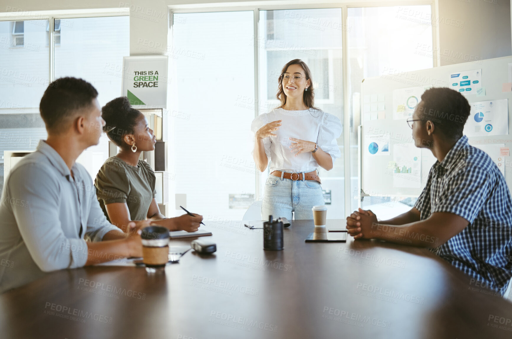 Buy stock photo Group of diverse businesspeople having a meeting in an office at work. Happy mixed race businesswoman talking while doing a presentation at a table for coworkers. Businesspeople planning together