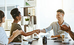 African american businesswoman and mixed race businessman shaking hands while their colleagues clap hands in support during a meeting at work. Boss shaking hands with a coworker during a workshop