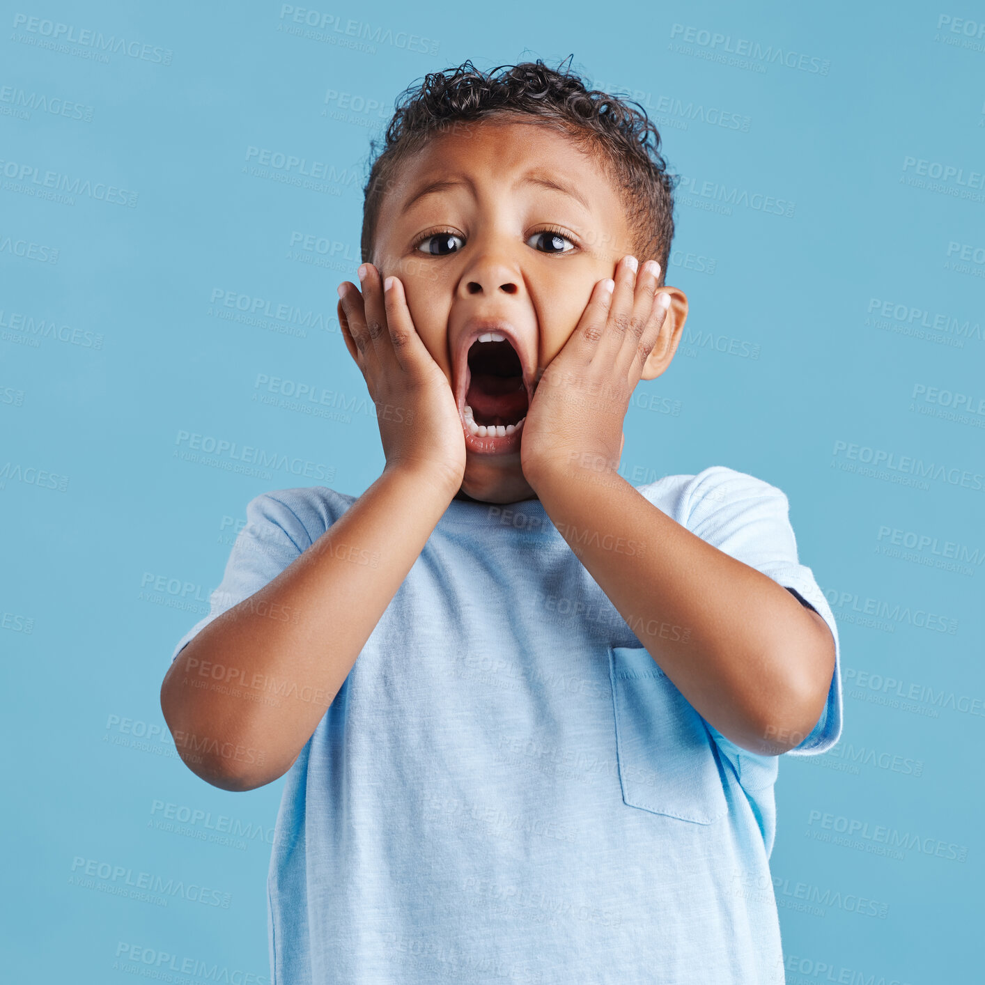 Buy stock photo Adorable little hispanic boy with hands on face and mouth open looking terrified and shocked showing true astonished reaction against a blue studio background