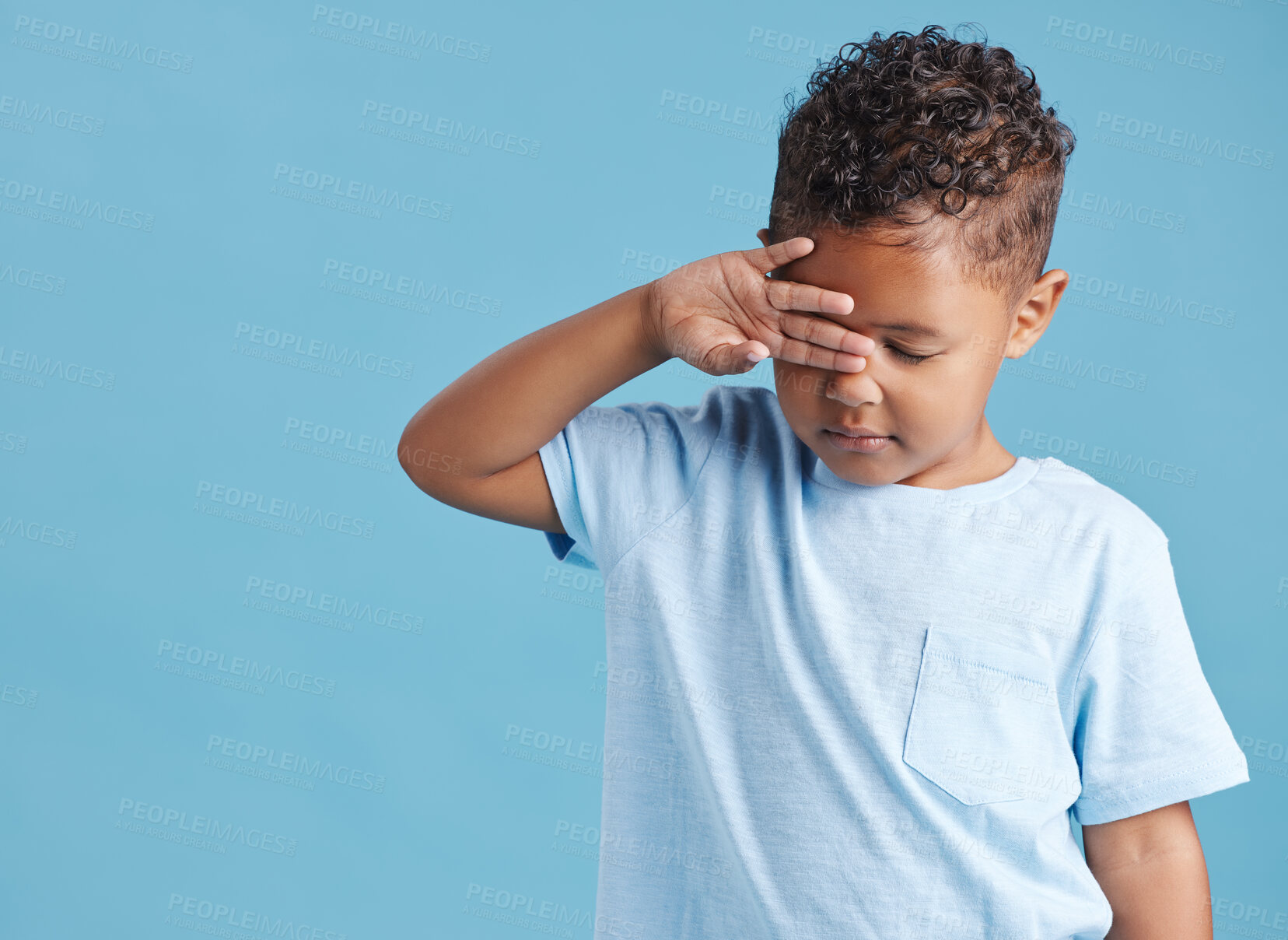 Buy stock photo Sad little hispanic boy looking sad and rubbing his eyes against a blue studio background. Unhappy preschooler crying on his first day