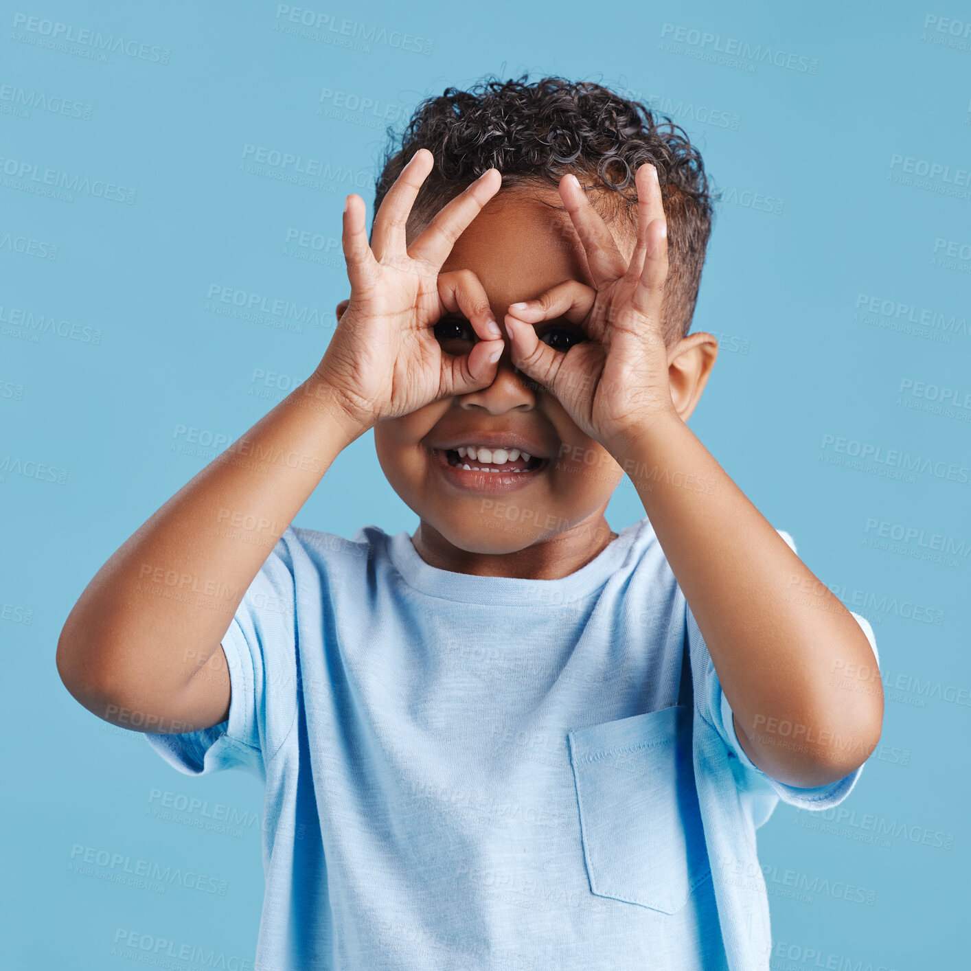 Buy stock photo Portrait of inquisitive nosy little boy looking through fingers shaped like binoculars against a blue studio background. Curious child exploring