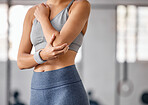 Closeup of one caucasian woman holding her sore elbow while exercising in a gym. Female athlete suffering with painful arm injury from fractured joint and inflamed muscles during workout. Struggling with stiff body cramps causing discomfort and strain