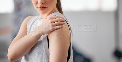 Buy stock photo Closeup of one caucasian woman holding her sore shoulder while exercising in a gym. Female athlete suffering with painful arm injury from fractured joint and inflamed muscles during workout. Struggling with stiff body cramps causing discomfort and strain