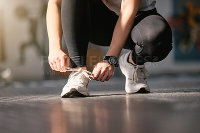Buy stock photo Closeup of one active caucasian woman tying her shoelaces while exercising in a gym. Female athlete fastening sneaker footwear for a comfortable fit and to prevent tripping during a training workout in a fitness centre