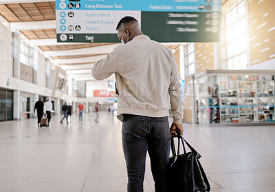 Buy stock photo Rear view of African american businessman travelling alone and standing in a train station while checking his travel times on his watch