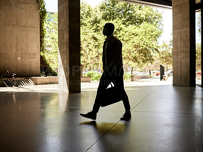 Silhouette of a businessman walking in a station on his way to work in the morning while carrying his bag