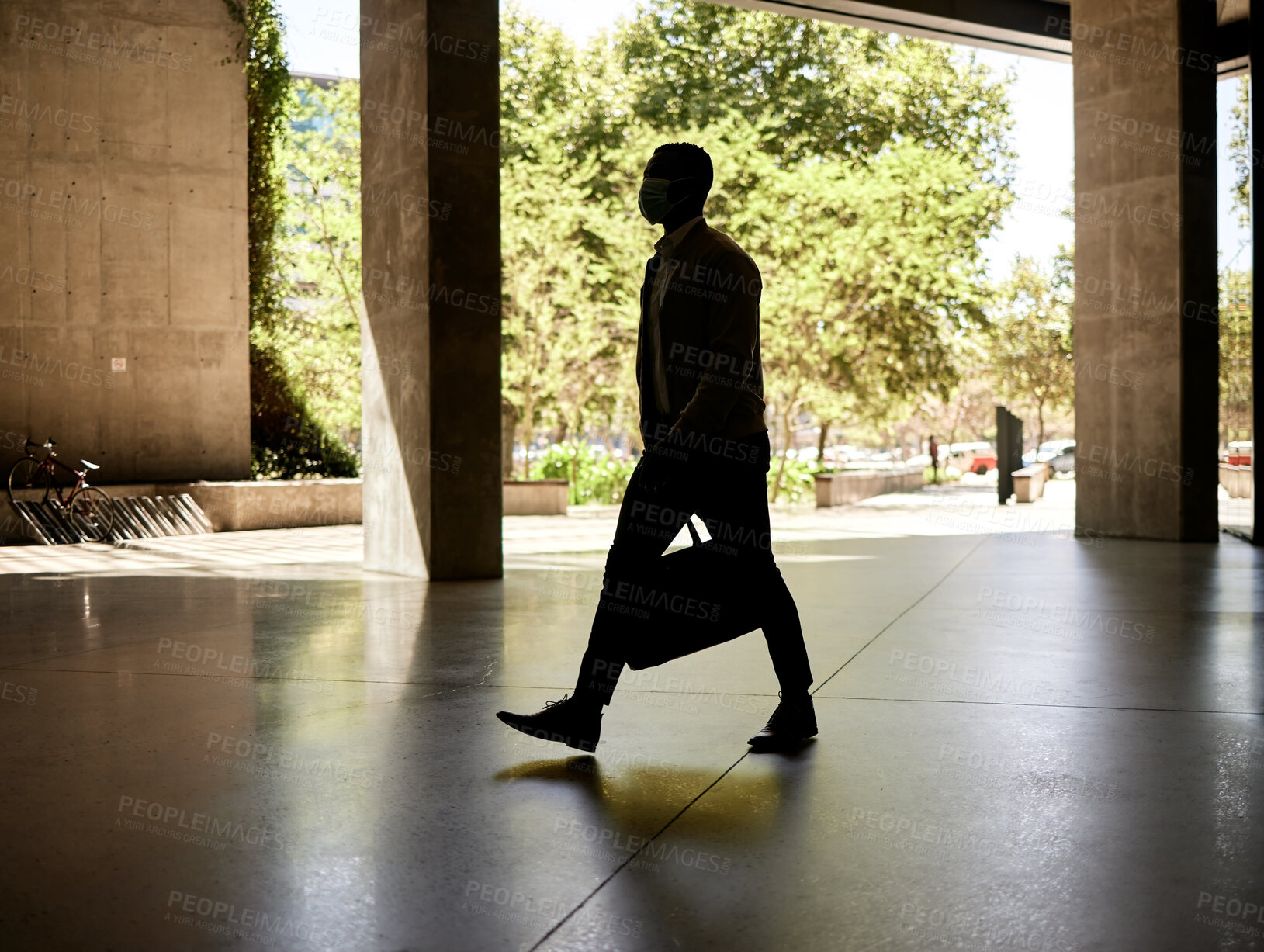Buy stock photo Silhouette of a businessman walking in a station on his way to work in the morning while carrying his bag
