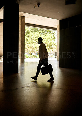 Silhouette of a businessman walking in a station on his way to work in the morning while carrying his bag