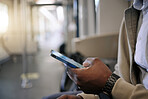 Closeup of Black businessman travelling in a train while using a cellphone. African american male using a wireless device while commuting on a train