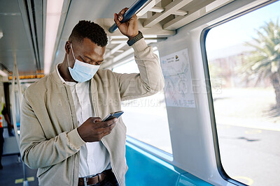 Buy stock photo Black businessman travelling alone. A young african american businessman using a cellphone while standing in the passage on a train during his commute to the city