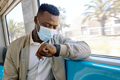 Black businessman travelling alone. A young african american businessman sitting on a seat while sitting at the window on a train and wearing a mask during his commute to the city