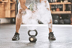 Dusting before power lifting. Bodybuilder getting ready to lift a heavy kettlebell. Athlete ready to lift weights. Sporty, muscular trainer using powder before a weight lifting routine.