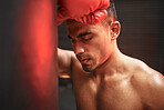 Closeup mixed race boxer man sparring with a punching bag in a fighting club gym. Male athlete working out in preparation for his upcoming fight. Handsome young martial artist training and practicing