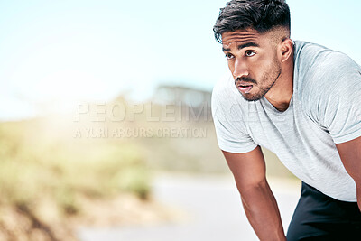 Buy stock photo Fit young mixed race man resting while exercising outdoors. Handsome hispanic male athlete taking a break and looking exhausted while working out outside. Cardio and endurance training for fitness