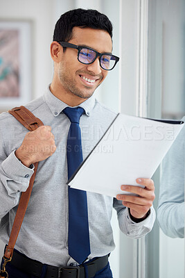 Buy stock photo Content mixed race businessman reading a report alone in an office at work. Hispanic male businessperson wearing glasses looking at a document while standing in an office