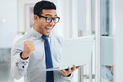 Buy stock photo Amazed young mixed race businessman standing and working on a laptop in an office at work. Joyful hispanic male businessperson looking shocked while cheering and holding a laptop at work