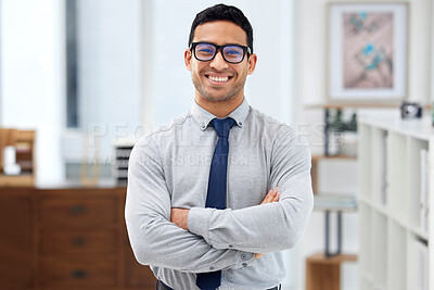 Buy stock photo Young cheerful mixed race businessman standing with his arms crossed alone in an office at work. Headshot of a confident hispanic businessperson wearing glasses while standing at work