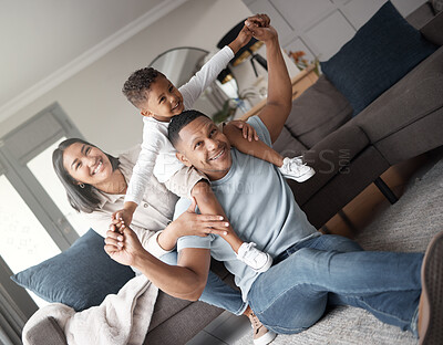 A happy mixed race family of three relaxing on the lounge floor and being playful together. Loving black family bonding with their son while playing fun games on the carpet at home