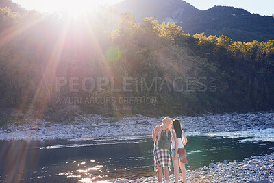 Two women next to a river taking a break during a hike in nature. Two friends hiking in nature enjoying the view and taking a break next to a river. Two women standing by a river enjoying the view