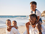 Carefree young african american family with two children walking along the beach. Loving mother and father carrying their daughter and son while spending time together on vacation