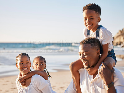 Buy stock photo Carefree young african american family with two children walking along the beach. Loving mother and father carrying their daughter and son while spending time together on vacation