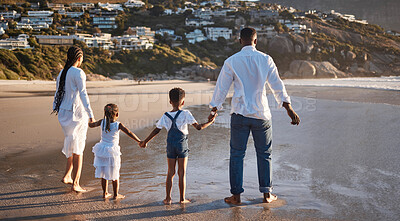 Buy stock photo Rear view of carefree young african american family with two children holding hands and looking at the view while getting their feet wet enjoying family vacation by the beach