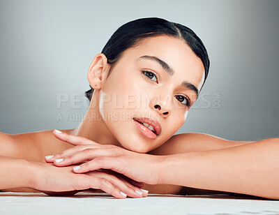 Buy stock photo Portrait of a beautiful mixed race woman with smooth soft skin in a studio. Hispanic model with healthy natural glowing skin looking confident against grey copyspace while doing routine skincare