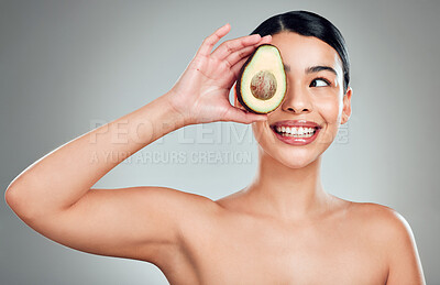 Buy stock photo A happy mixed race woman holding an avocado. Hispanic model smiling and promoting the skin benefits of a healthy diet against a grey copyspace background