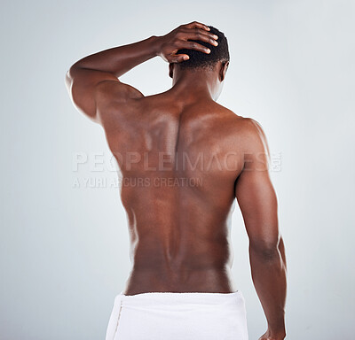 Buy stock photo Rear view of one African American fitness model posing topless in a towel and looking muscular. Black male athlete rubbing his head while isolated on grey copyspace in a studio