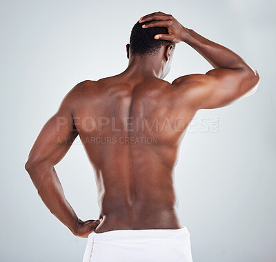 Buy stock photo Rear view of one African American fitness model posing topless in a towel and looking muscular. Black male athlete rubbing his head while isolated on grey copyspace in a studio