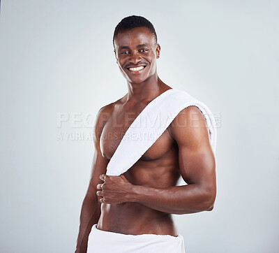 Buy stock photo Portrait of a smiling African American fitness model posing topless in a towel and looking muscular. Happy black male  athlete isolated on grey copyspace in a studio after a shower